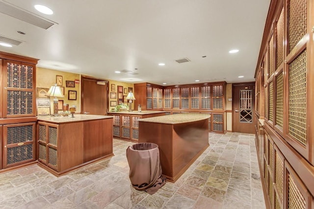 25 E Superior St Unit 2501, Chicago, IL 60611 - kitchen featuring a center island, glass insert cabinets, brown cabinetry, light stone finish flooring, and recessed lighting