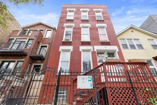 view of front facade with a fenced front yard, brick siding, cooling unit, and a gate