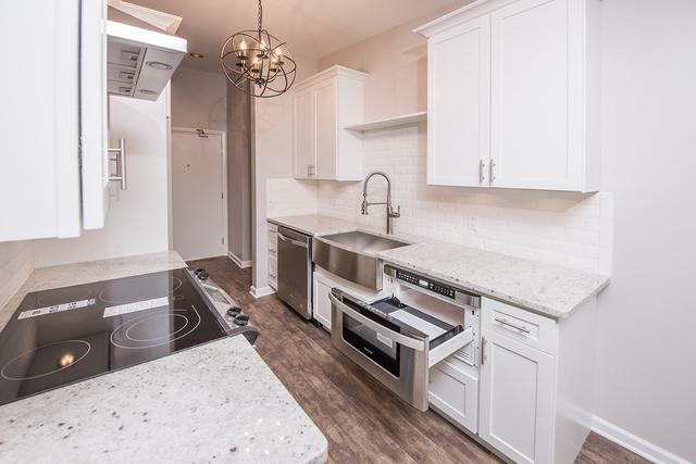 kitchen with dishwasher, a chandelier, a sink, and dark wood-type flooring