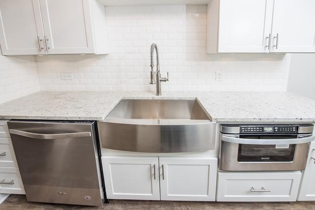 kitchen with dishwasher, decorative backsplash, white cabinets, and a sink