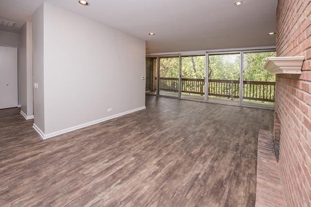 unfurnished living room featuring dark wood-style floors, baseboards, recessed lighting, and a fireplace