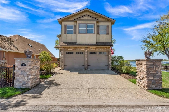 craftsman-style house featuring stone siding, an attached garage, concrete driveway, fence, and a water view