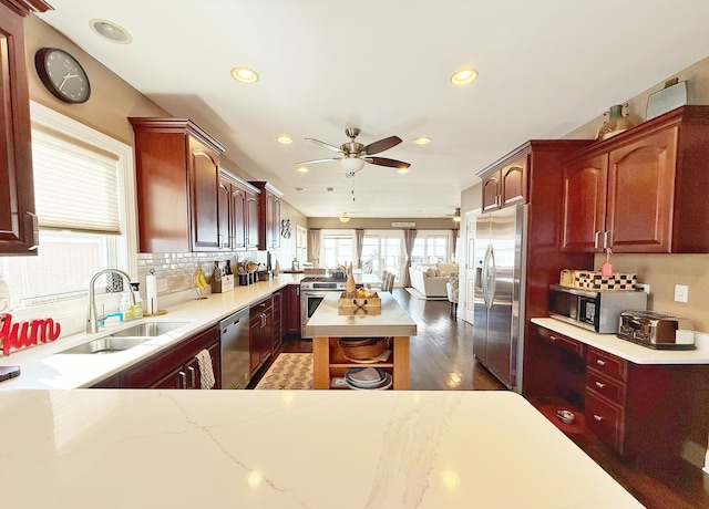 kitchen with appliances with stainless steel finishes, a sink, reddish brown cabinets, recessed lighting, and tasteful backsplash