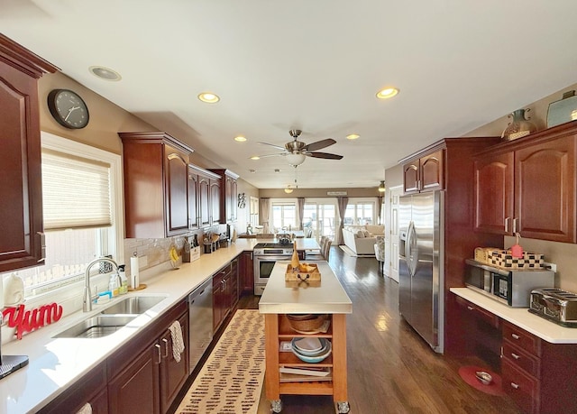 kitchen featuring appliances with stainless steel finishes, a sink, open floor plan, open shelves, and recessed lighting