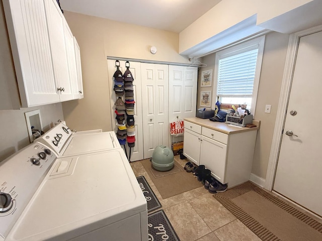 washroom featuring cabinet space, washing machine and dryer, and tile patterned floors