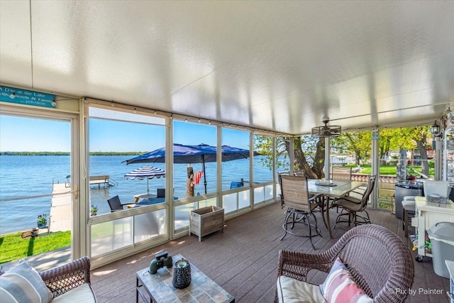 sunroom / solarium featuring a water view, carpet, and a wall of windows
