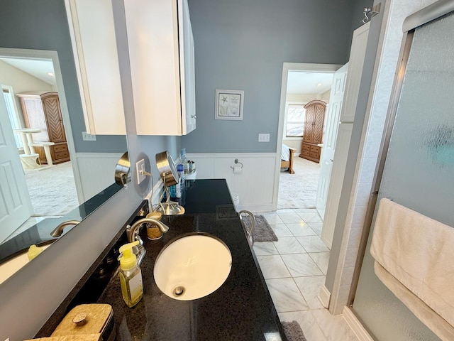 full bath with wainscoting, a stall shower, and double vanity
