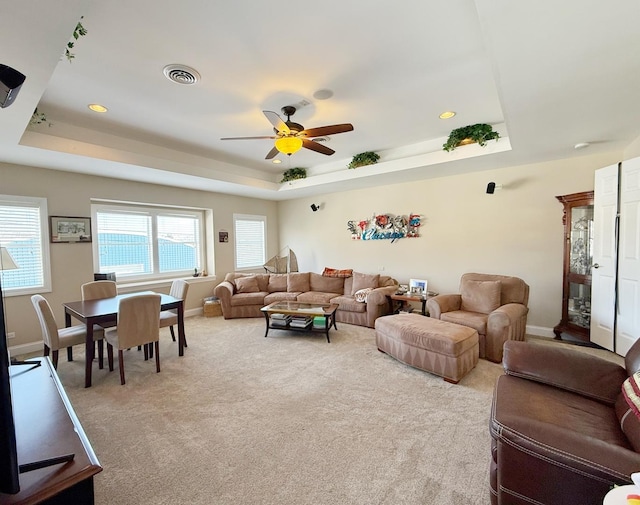 living area featuring a raised ceiling, ceiling fan, light carpet, baseboards, and recessed lighting