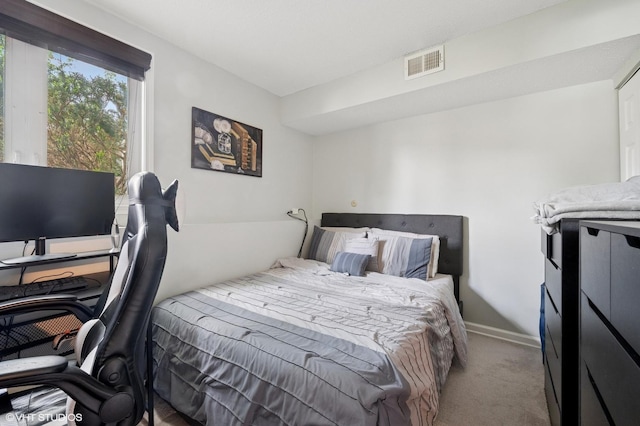 carpeted bedroom featuring baseboards and a desk