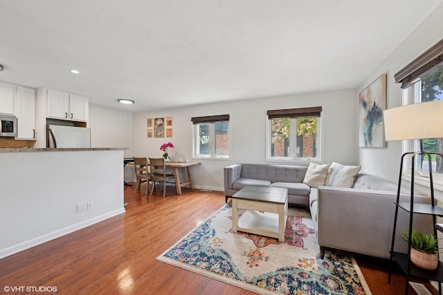 living area with plenty of natural light, wood finished floors, baseboards, and recessed lighting