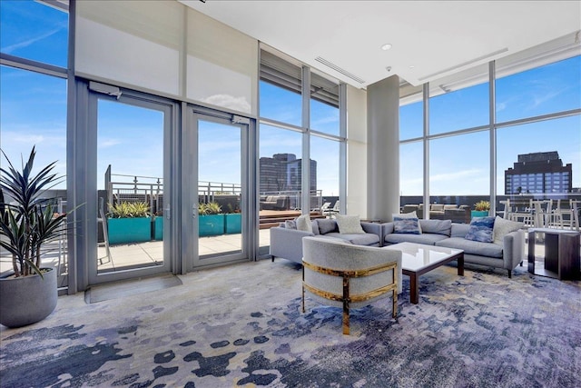 living area featuring a wall of windows, carpet, a towering ceiling, and a city view