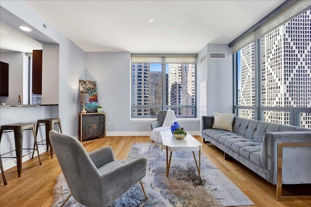 living area with plenty of natural light, baseboards, light wood-style floors, and a city view