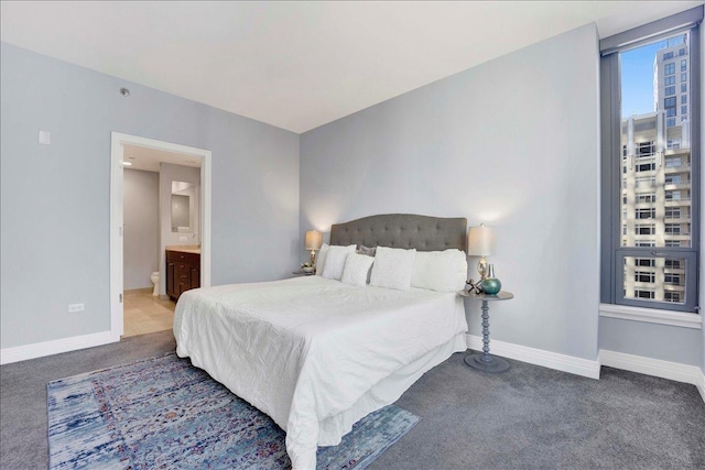 carpeted bedroom featuring baseboards and ensuite bath