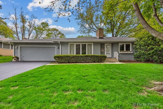 view of front facade with a chimney, an attached garage, a front yard, and asphalt driveway