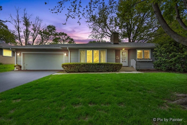ranch-style house featuring a chimney, a garage, a lawn, and concrete driveway