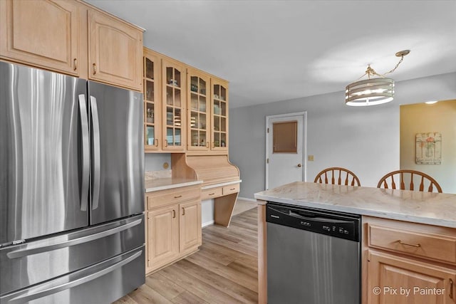 kitchen featuring appliances with stainless steel finishes, light brown cabinets, light wood-type flooring, glass insert cabinets, and light stone counters