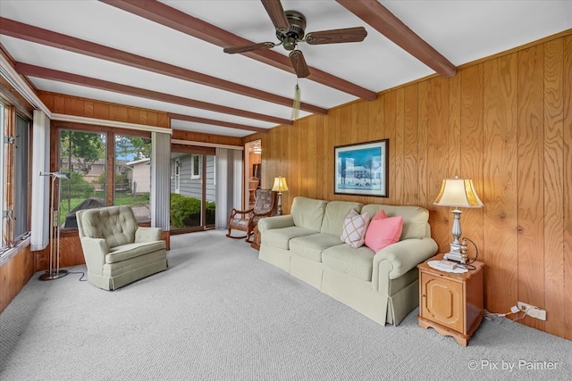 living room with beamed ceiling, carpet flooring, wooden walls, and a ceiling fan