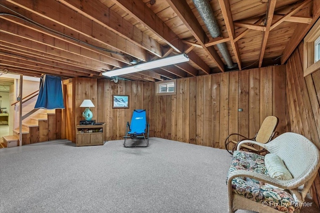 sitting room featuring carpet, wooden walls, and stairway