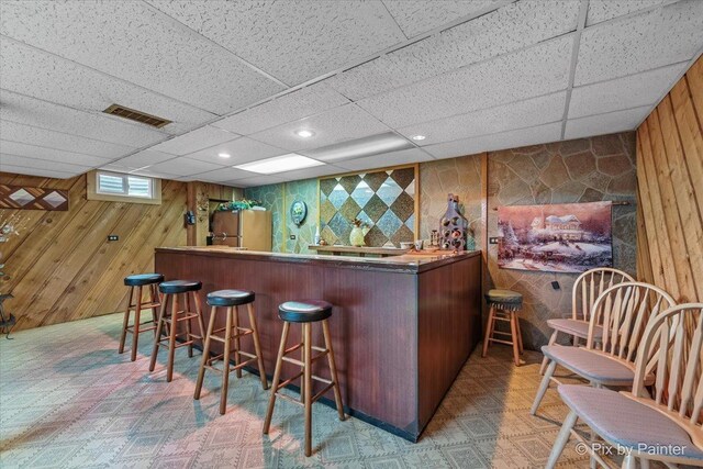 indoor bar featuring a paneled ceiling, wooden walls, and recessed lighting