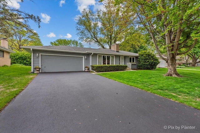 view of front of house with a garage, a chimney, driveway, and a front lawn