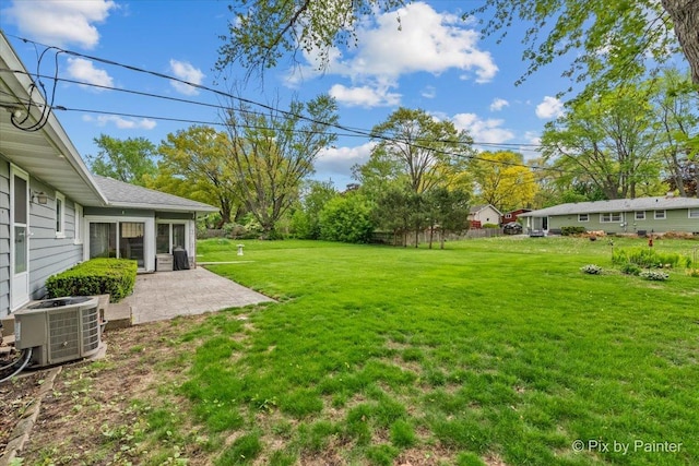 view of green lawn featuring central air condition unit and a patio area