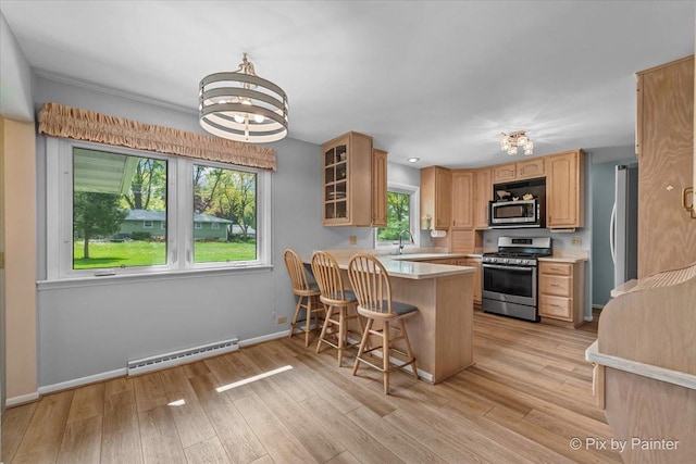 kitchen featuring stainless steel appliances, a chandelier, a peninsula, light countertops, and glass insert cabinets