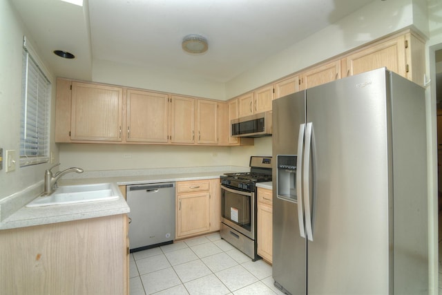 kitchen with appliances with stainless steel finishes, light brown cabinetry, a sink, and light tile patterned floors