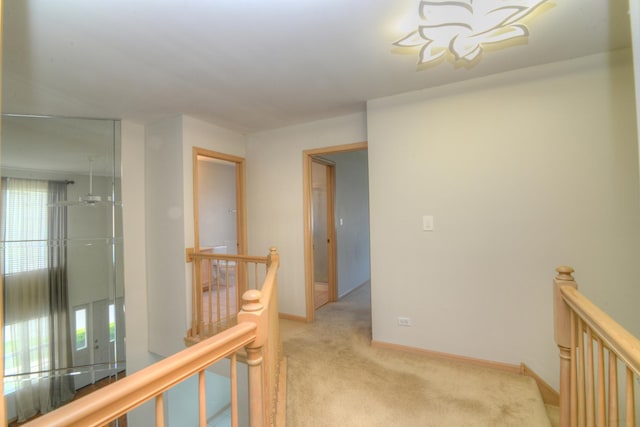 hallway featuring an upstairs landing, light carpet, and baseboards
