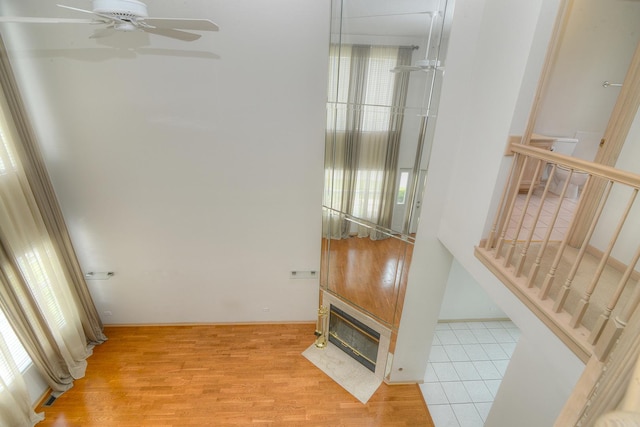 stairs featuring ceiling fan, a fireplace with flush hearth, and wood finished floors