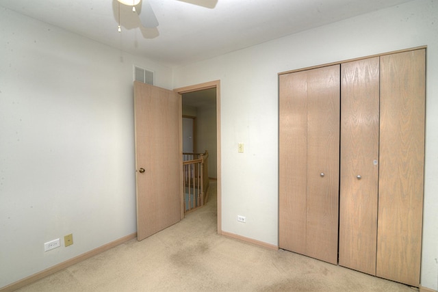 unfurnished bedroom featuring light carpet, a closet, baseboards, and ceiling fan