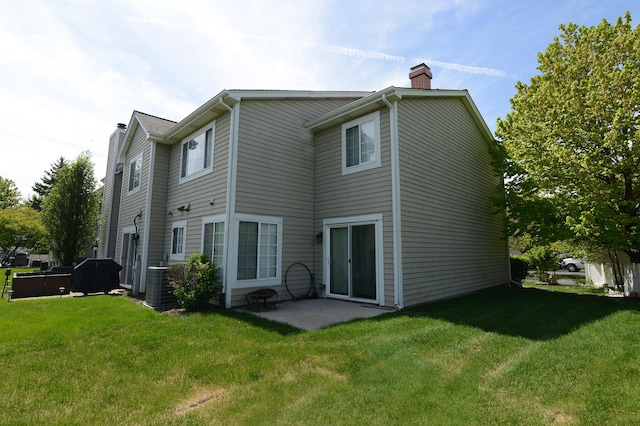 back of property featuring a chimney, a yard, central AC, and a patio area
