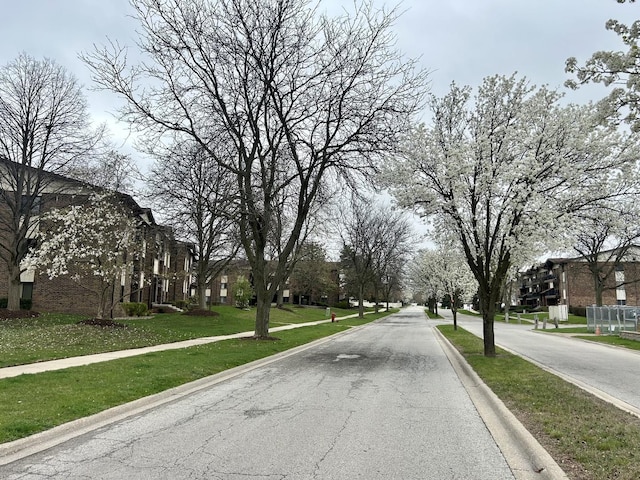view of asphalt street featuring sidewalks, curbs, and a residential view
