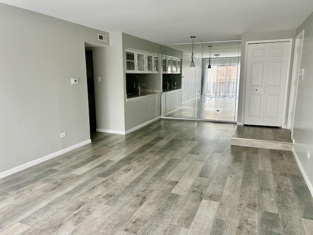 unfurnished living room featuring wood finished floors and baseboards