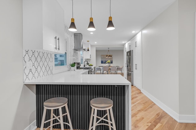 274 University Dr, Buffalo Grove, IL 60089 - kitchen featuring ventilation hood, appliances with stainless steel finishes, a breakfast bar, white cabinetry, and a peninsula