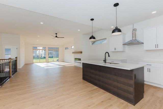 1904 Dunraven Rd, Bloomington, IL 61704 - kitchen featuring a sink, wall chimney exhaust hood, a fireplace, decorative backsplash, and light wood finished floors