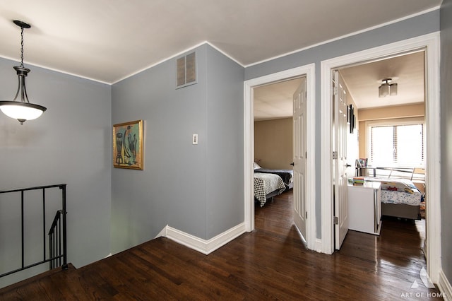 corridor with wood finished floors, baseboards, and ornamental molding