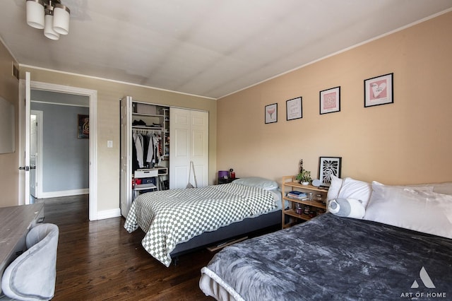 bedroom featuring wood finished floors, ornamental molding, a closet, and baseboards