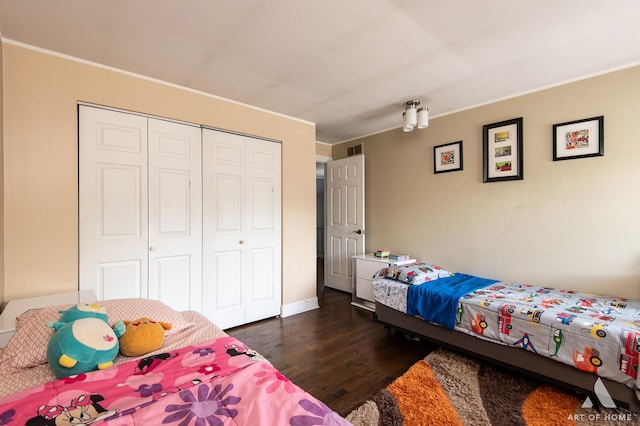 bedroom with dark wood-style floors, a closet, crown molding, and baseboards