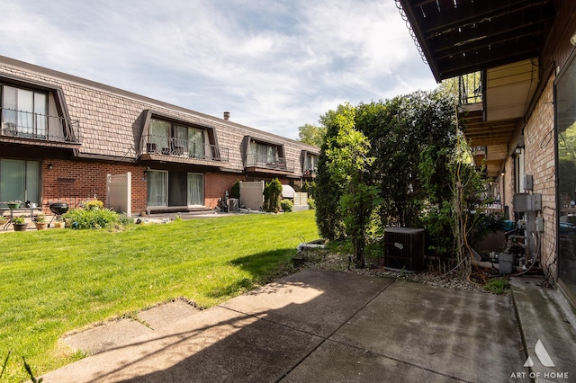 view of green lawn with central AC and a patio