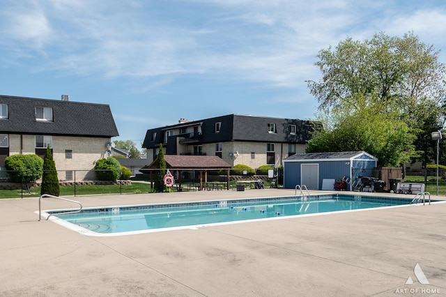 community pool featuring fence, a patio, an outbuilding, and a shed