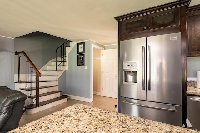 kitchen with stainless steel refrigerator with ice dispenser, dark brown cabinets, and light wood-style floors