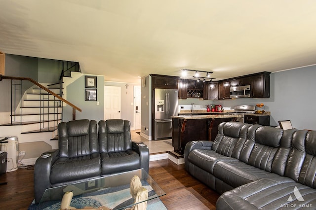 living room with dark wood-style floors, stairs, and track lighting