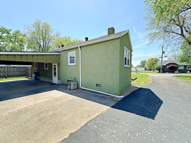 925 N Otter Creek Rd, Streator, IL 61364 - view of side of home with driveway, a carport, a chimney, fence, and stucco siding