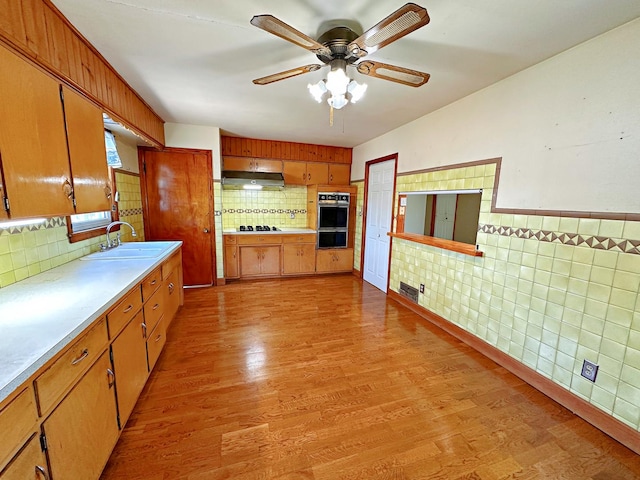 925 N Otter Creek Rd, Streator, IL 61364 - kitchen featuring a sink, light countertops, under cabinet range hood, light wood-type flooring, and tile walls