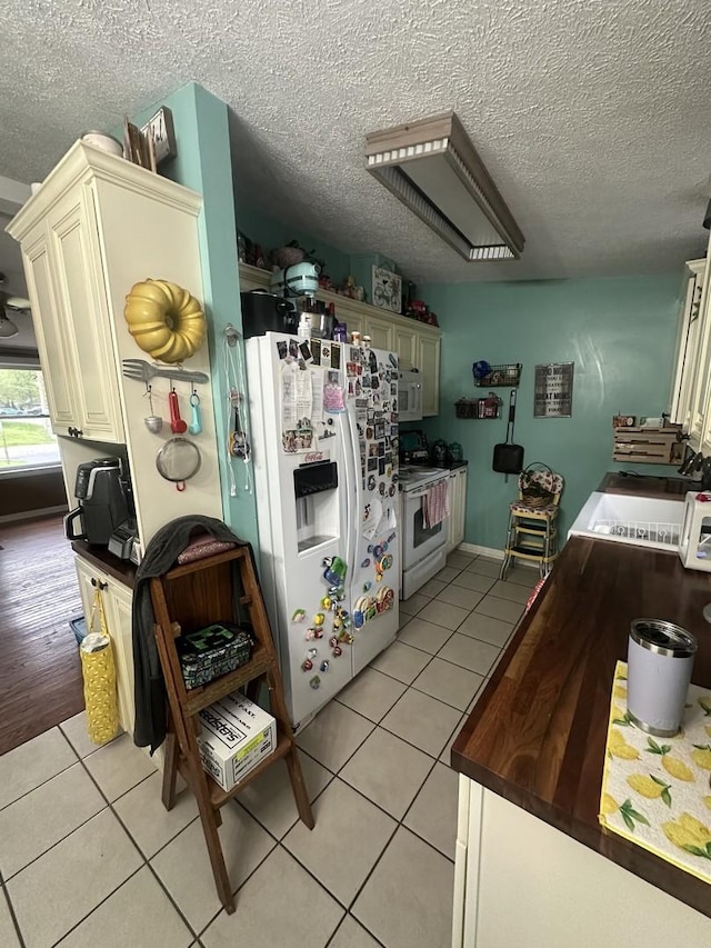 795 N Erie St, Braidwood, IL 60408 - kitchen featuring white appliances, light tile patterned flooring, a textured ceiling, a sink, and dark countertops