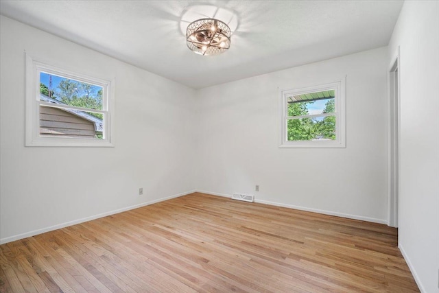 empty room featuring plenty of natural light, light wood-type flooring, and baseboards
