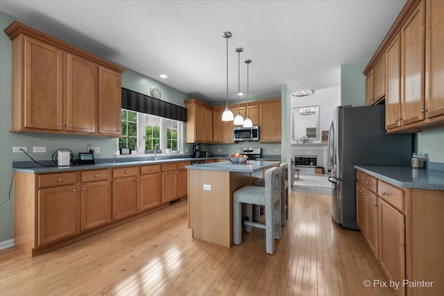 9 Laurel Valley Ct, Lake In The Hills, IL 60156 - kitchen featuring appliances with stainless steel finishes, a center island, a breakfast bar area, brown cabinetry, and light wood-style flooring