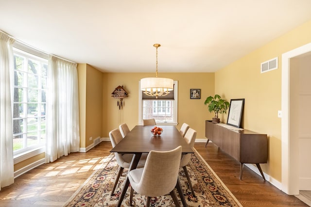 dining space with a chandelier, wood finished floors, healthy amount of natural light, and baseboards