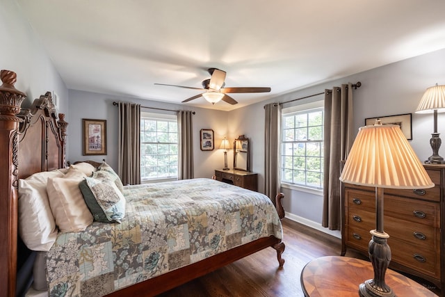 bedroom featuring multiple windows, dark wood-type flooring, a ceiling fan, and baseboards