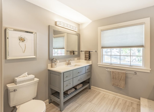 bathroom with toilet, baseboards, and vanity